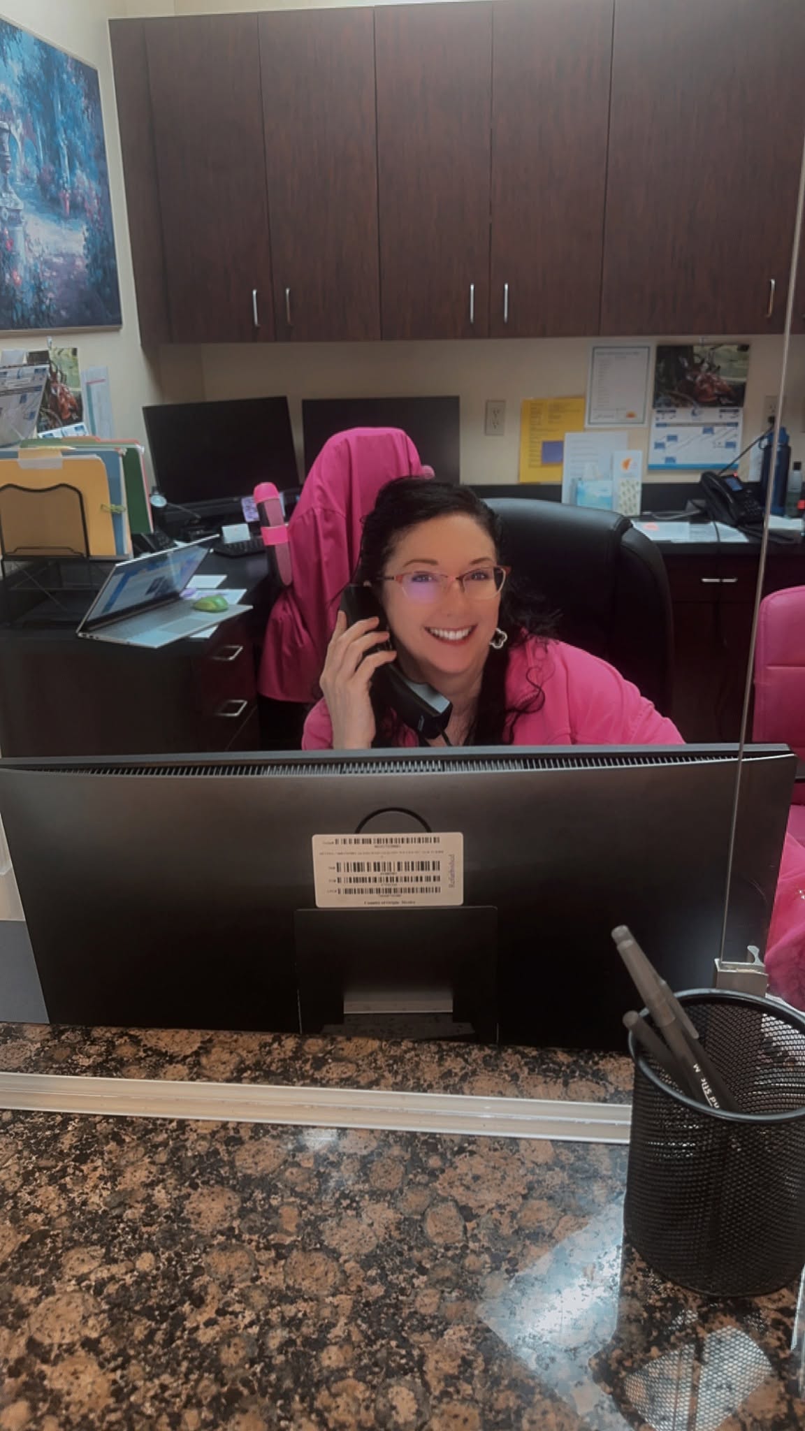 Staff member at reception desk answering phone call in Florida Bladder Institute office